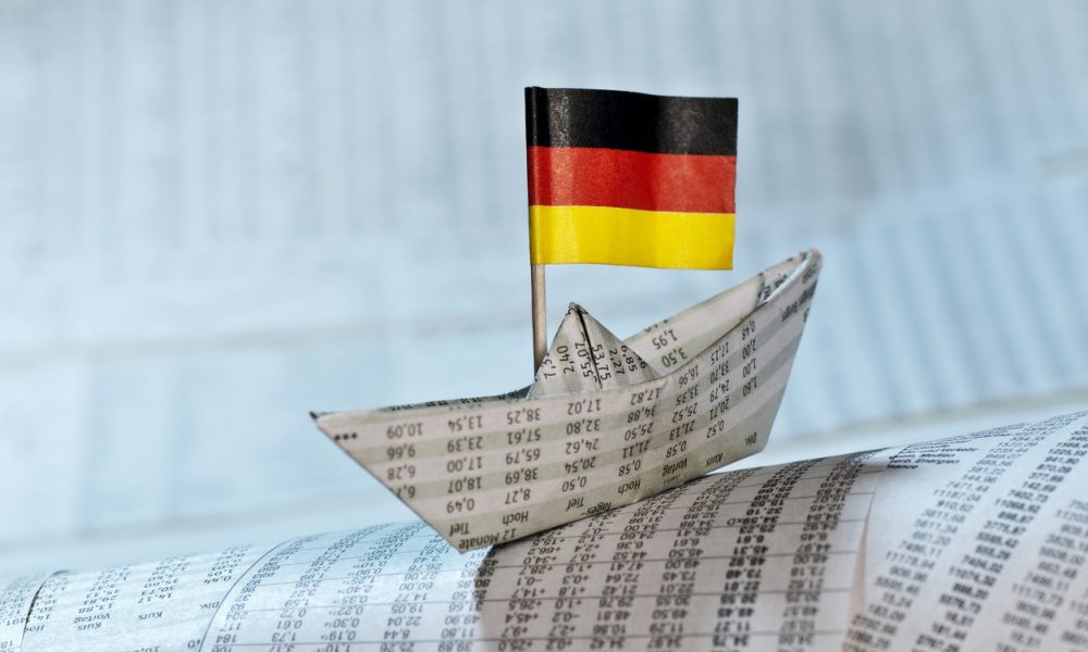 Ein Papierschiff mit deutscher Flagge steht auf Papier.